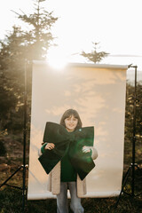 M&auml;dchen mit gr&uuml;ner Masche in der Hand steht vor beigem Studiohintergrund in der Natur