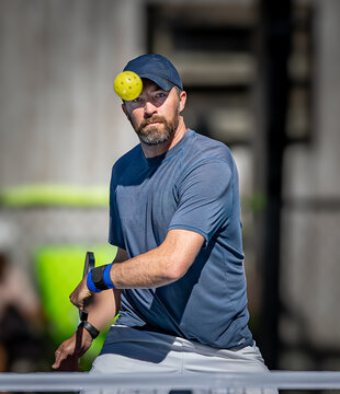Male picklball player keeps his eyes on the ball as he is about to hit a slice backhand volley