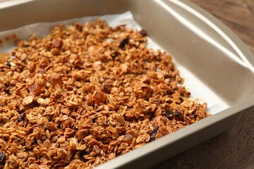 Tasty granola with dried fruits in tray on wooden table, closeup