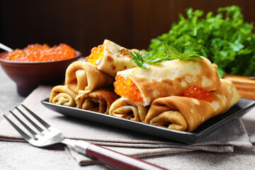 Tasty crepes with red caviar, sour cream and parsley on grey table, closeup