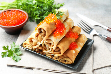 Tasty crepes with red caviar and parsley on grey table, closeup