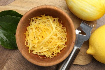 Lemon zest, fresh fruits and zester tool on wooden table, flat lay