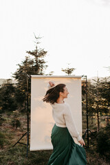 Dunkelhaarige Frau, 40+, vor einem beigen Hintergrund in der Natur