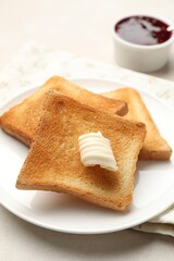 Slices of toasted bread, butter and jam on beige table, closeup