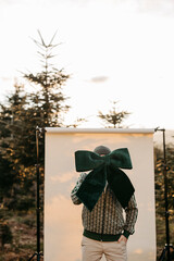 Mann mit gr&uuml;ner Masche in der Hand steht vor beigem Studiohintergrund in der Natur