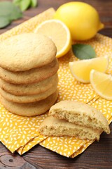 Tasty lemon cookies and fruit slices on wooden table, closeup