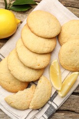 Tasty lemon cookies and fruit slices on wooden table, flat lay
