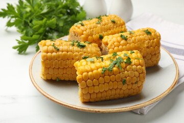 Pieces of boiled corncobs with parsley on white marble table, closeup
