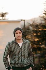 Mann in gr&uuml;ner Weste vor beigem Studiohintergrund in freier Natur