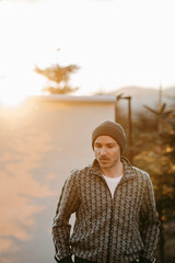 Mann in gr&uuml;ner Weste vor beigem Studiohintergrund in freier Natur