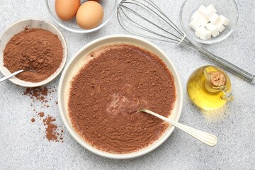 Chocolate dough, whisk and ingredients on grey textured table, flat lay