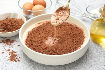 Dripping chocolate dough from spoon at grey textured table, closeup