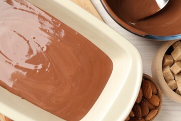 Liquid chocolate dough, brown sugar and nuts on wooden table, flat lay