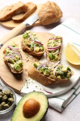 Delicious bruschettas with avocado, onion and microgreens served on light table, closeup