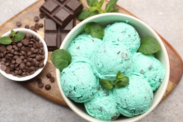 Tasty mint chocolate chip ice cream and waffle cones on wooden table, flat lay