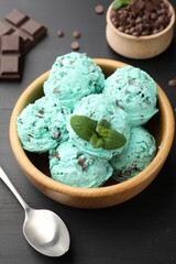 Yummy mint chocolate chip ice cream served on black wooden table, closeup