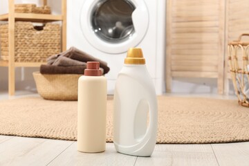 Bottles of detergent and laundry basket with towels on floor indoors