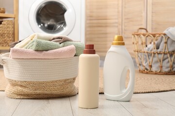 Bottles of detergent and baskets with laundry on floor indoors