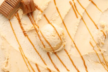 Tasty ice cream with caramel sauce as background, top view