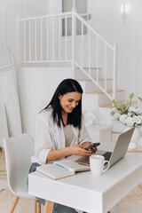 Woman multitasking on devices, Professional woman coordinating tasks on multiple electronic devices, Entrepreneurina woman enthusiastically managing her work using smartphone and laptop equipment