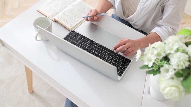 Caucasian woman skillfully enters data with tools, Closeup of woman using laptop and pen for multitasking, Bright minimalist workspace showing woman accurately inputting data with multiple tools