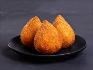 Black plate with fried savory Coxinha snacks
