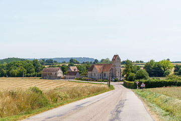 A rural road with a church and a few houses in France Normandy. The road is empty and the sky is clear