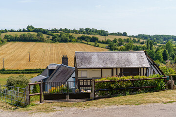 An old half-timbered building standing in a field in fine weather in the town of Camembert, France The clear and blue photo was taken in clear weather