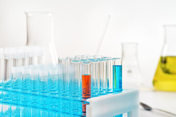Lab table with test tubes stand red and blue liquid in, more chemical glass background