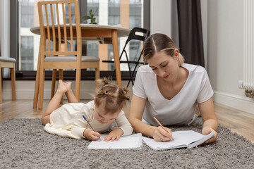 Young working mother planning home budget, remote work at home, writting ideas, plans, to do list. Woman with child creativity in notes, freelance,