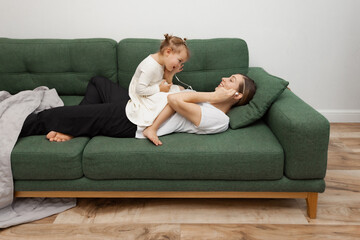 Smiling mother and daughter enjoying music through in-ear headphones