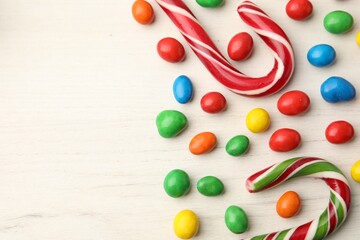 Delicious colorful candies on white table, flat lay. Space for text