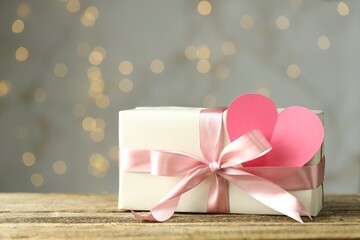 Saint Valentine's day. Beautiful gift with paper heart on wooden table against grey background with bokeh effect. Space for text