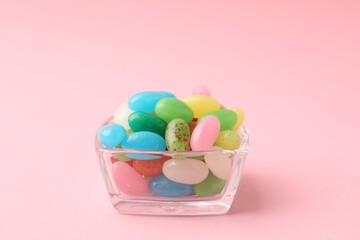 Delicious colorful candies in bowl on pink background, closeup