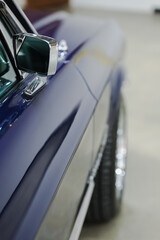 Side mirror and window close-up details of a blue vintage American Car. Vertical classic vehicle photo with copy space.