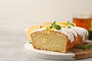 Delicious lemon cake with glaze, fresh fruit slices and mint on gray table, closeup. Space for text