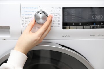 Woman turning on white washing machine, closeup