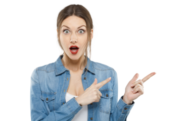 Portrait of a shocked young woman in a denim shirt pointing with both hands to the side