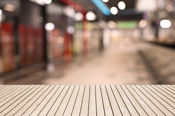 Empty wooden table against blurred view of shopping mall. Space for design
