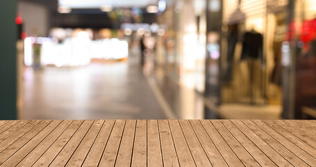 Empty wooden table against blurred view of shopping mall. Space for design