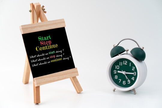 A standing chalkboard with markers displaying a Start-Stop-Continue framework. The scene illustrates a structured Start-Stop-Continue exercise, commonly used for evaluating team performance