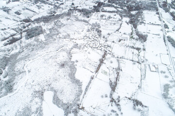 Fototapeta premium Aerial View of a Small Village Surrounded by Snow Covered Fields The Concept of Isolation