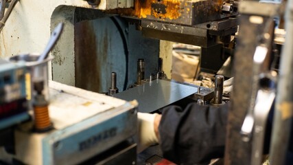 Factory Worker Loading Metal Sheet into Press Machine with Automatic Feeding Equipment