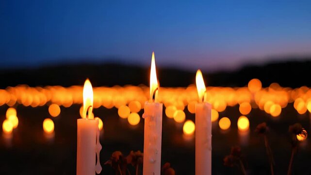 A serene night scene of a memorial candlelight vigil with a field of burning candles and a beautiful bokeh background.