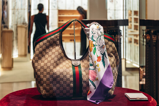 Nice, France &ndash; August 2, 2025: Gucci silk Flora scarf displayed with a Gucci monogram handbag in a luxury store window