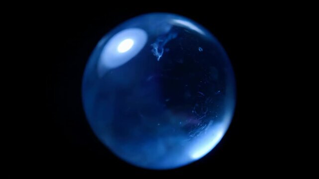 A mysterious glowing blue crystal orb with a swirling ethereal nebula inside against a black background