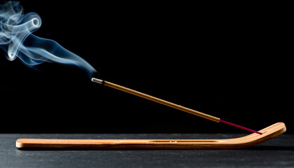 Burned Out Incense Stick. Thin trail of smoke rising from a recently burned incense stick, black background.