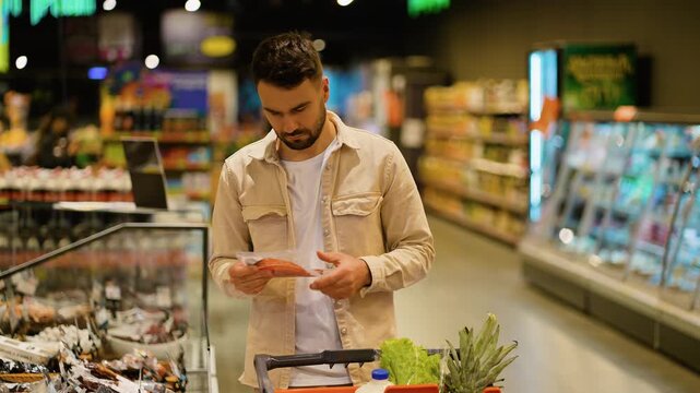 Young man choosing sliced meat in supermarket grocery store