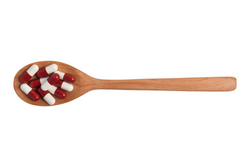 Medicine capsules with wooden spoon on a white background, top view.