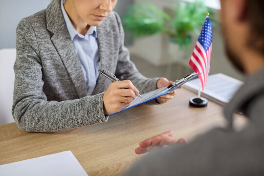 Consular visa interview with USA officer reviewing documents in public services or embassy. Immigration applicant answers questions and presents forms during a citizenship review seeking approval. 